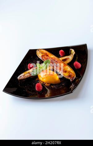 Eine gebratene Banane mit Passionsfrucht-Sorbet und Himbeeren Stockfoto