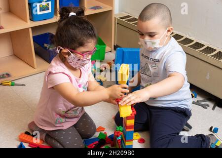Bildung Vorschule 3-4-jährige Junge und Mädchen spielen zusammen Gebäude mit bunten Plastikziegeln (Duplo) Stockfoto