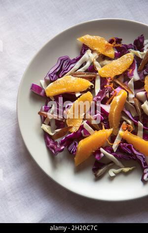 Ein roher und gesunder Wintersalat mit Rotkohl, Weißkohl, Datteln, Orange, Orangenschale Stockfoto