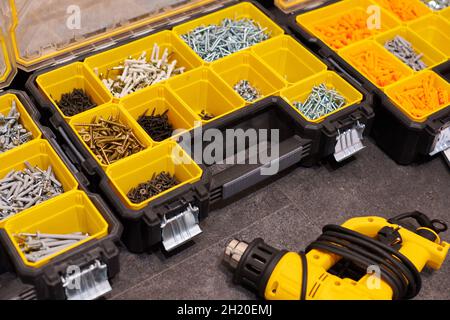 Zwei Aufbewahrungsboxen auf dem Boden mit kleinen Bauobjekten. Viele Staufächer gefüllt mit Zubehör mit Schrauben, Muttern, Schrauben, Nägeln und Stockfoto