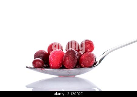 Mehrere frische Bio-Preiselbeeren mit Metalllöffel, Nahaufnahme, isoliert auf Weiß. Stockfoto