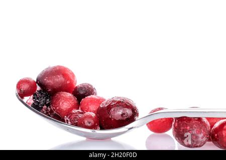 Mehrere frische Bio-Preiselbeeren mit Metalllöffel, Nahaufnahme, isoliert auf Weiß. Stockfoto