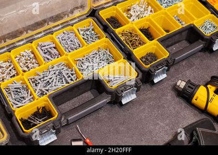 Zwei Aufbewahrungsboxen auf dem Boden mit kleinen Bauobjekten. Viele Staufächer gefüllt mit Zubehör mit Schrauben, Muttern, Schrauben, Nägeln und Stockfoto