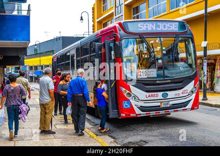 San José Costa Rica 04. Januar 2021 Bunte Busbusse im belebten Verkehr und Stadtbild mit Geschäften Menschen und Autos in San José Costa Rica. Stockfoto