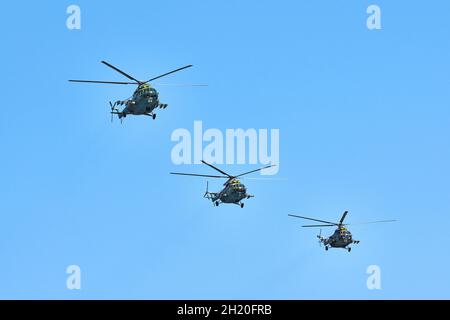 Drei Militärhubschrauber fliegen in hellblauem Himmel, während sie Demonstrationsflüge durchführen, kopieren Raum. Das Kunstflugteam führt einen Flug bei der Flugshow durch Stockfoto