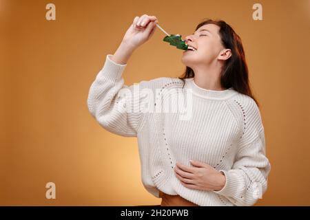 Die Frau versucht einen süßen Weihnachtslollipop in Form einer Tanne. Stockfoto