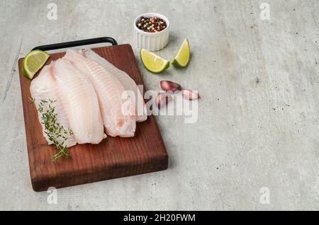 Rohes Tilapia-Fischfilet mit Gewürzen über Holzbrett. Stockfoto