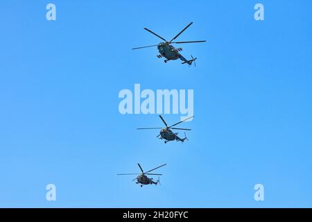 Drei Militärhubschrauber fliegen in hellblauem Himmel, während sie Demonstrationsflüge durchführen, kopieren Raum. Das Kunstflugteam führt einen Flug bei der Flugshow durch Stockfoto