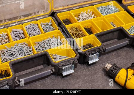 Zwei Aufbewahrungsboxen auf dem Boden mit kleinen Bauobjekten. Viele Staufächer gefüllt mit Zubehör mit Schrauben, Muttern, Schrauben, Nägeln und Stockfoto