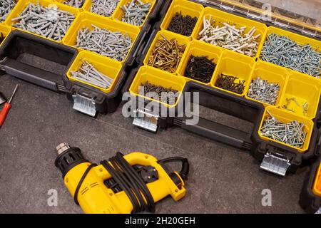 Zwei Aufbewahrungsboxen auf dem Boden mit kleinen Bauobjekten. Viele Staufächer gefüllt mit Zubehör mit Schrauben, Muttern, Schrauben, Nägeln und Stockfoto