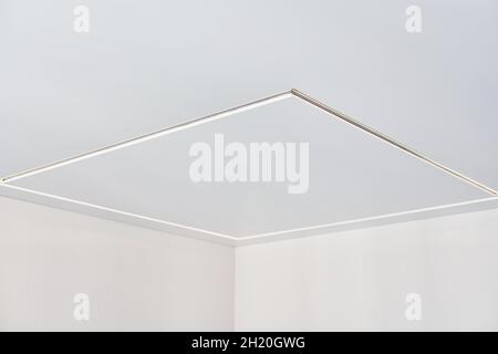 Abgehängte Decke mit quadratischer LED-Streifenlampe in leerem Raum in der Wohnung oder im Haus. Weiße Stretch-Decke mit matter körniger Textur. Renovierung des Hauses Stockfoto