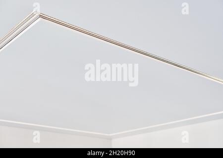 Abgehängte Decke mit quadratischer LED-Streifenlampe in leerem Raum in der Wohnung oder im Haus. Weiße Stretch-Decke mit matter körniger Textur. Renovierung des Hauses Stockfoto