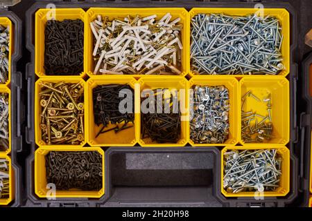 Aufbewahrungsbox mit kleinen Bauobjekten für die Werkstatt, Draufsicht. Viele Aufbewahrungsfächer mit Baukästen, die Schrauben und Muttern enthalten Stockfoto