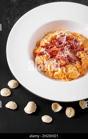 Teller mit Olecchiette-Pasta mit Kürbiscreme und gebratenem Speck Stockfoto