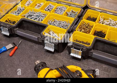 Zwei Aufbewahrungsboxen auf dem Boden mit kleinen Bauobjekten. Viele Staufächer gefüllt mit Zubehör mit Schrauben, Muttern, Schrauben, Nägeln und Stockfoto