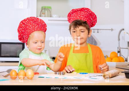 Zwei Jungen schneiden Teig aus Cookies in Herzform Stockfoto