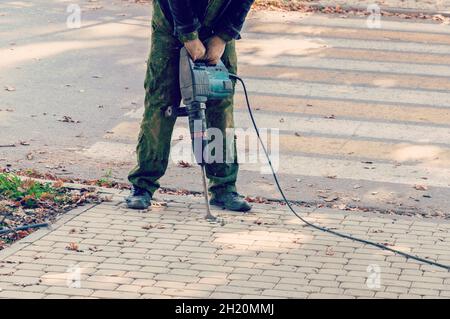 Arbeiter mit pneumatischen Hammerbohrgeräten. Straßenreparatur funktioniert mit Presslufthammer Stockfoto