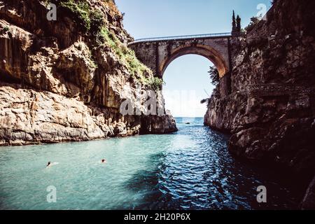 Fiordo di Furor ist eine gewölbte Steinbrücke, die diese eindrucksvolle Schlucht mit einem winzigen, felsigen Strand an seiner Basis überquert. Stockfoto