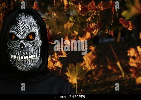 Nahaufnahme des grimmigen Reaper. Mann in Totenmaske mit Feuerfl Stockfoto