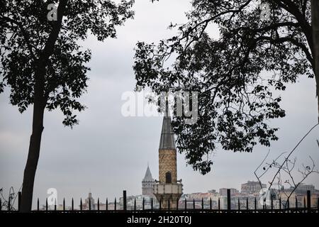 Minarett einer Moschee Blick vom Gulhane Park istanbul mit Antiker Galata Tower Hintergrund während des bewölkten und regnerischen Tages in istanbul im März Stockfoto