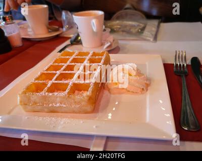 Berühmte belgische Waffel mit Schlagsahne auf einem Teller serviert. Fotografiert in der historischen Stadt Brügge, Belgien. Stockfoto