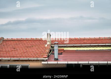 Rote und Zementfliesen Dachdeckung und Rauchloch mit blauem Himmel und weißen Wolken Hintergrund Stockfoto