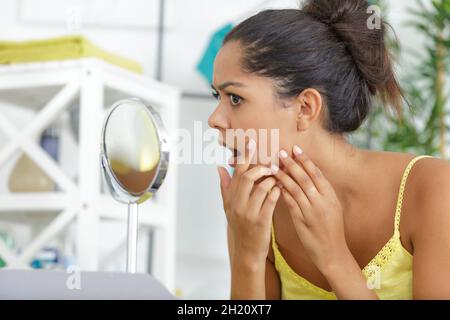 Junge Frau, die ihre Haut überprüft Stockfoto