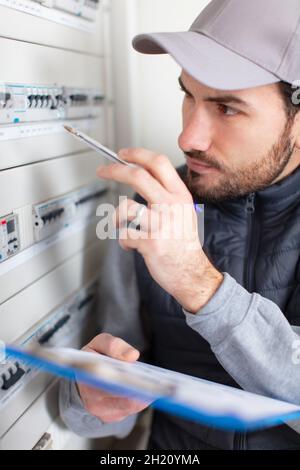 Elektroinstallateur für junge Erwachsene, die Ausrüstung im Sicherungskasten verschrauben Stockfoto