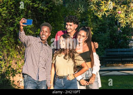 Eine Gruppe multiethnischer Freunde, die ein Selfie mit einem Mobilmobil machen, das in einem Park steht Stockfoto