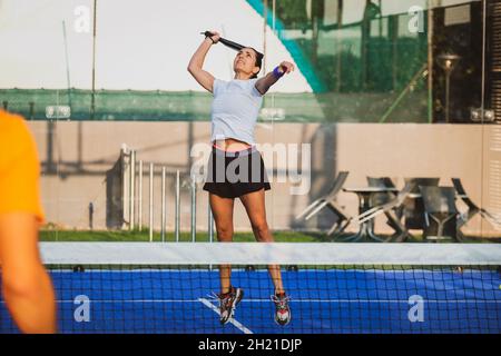 Der junge Lehrer überwacht den Padel-Unterricht für seine Schülerin - Coach lehrt Mädchen, wie man Padel auf dem Tennisplatz im Freien spielt Stockfoto