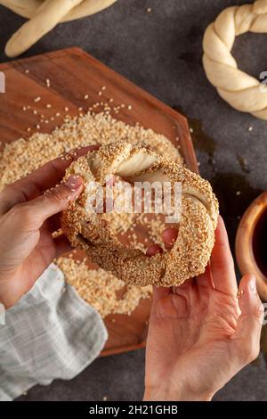 Köstlicher türkischer Bagel mit Sesamsamen, auch bekannt als Susamli simit. Bild von oben zeigt das Formen des geflochtenen Teigs und das Aufkleben von Sesam auf der Brandung Stockfoto