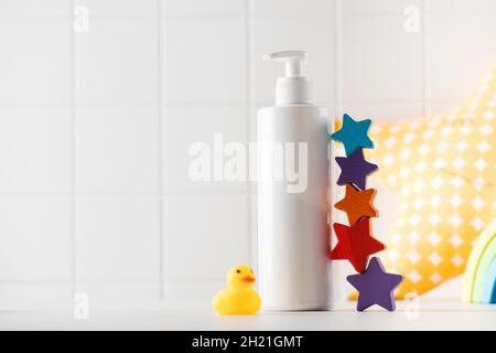 Leere Flasche Baby Hautpflegeprodukt und kleine Spielzeuge stehen auf dem Tisch im Badezimmer Stockfoto