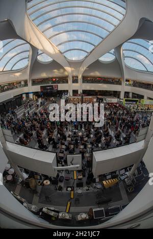 Das City of Birmingham Symphony Orchestra tritt unter den Abfluß-/Ankunftsbrettern in der New Street Station / Grand Central auf, wobei die Zuschauer die Krone aufsetzen. Stockfoto