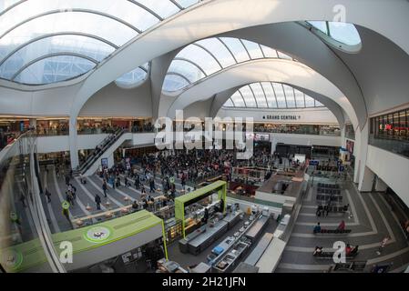 Das City of Birmingham Symphony Orchestra tritt unter den Abfluß-/Ankunftsbrettern in der New Street Station / Grand Central auf, wobei die Zuschauer die Krone aufsetzen. Stockfoto