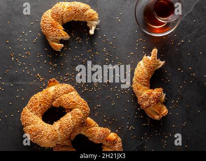 Köstlicher türkischer Bagel mit Sesamsamen, bekannt als Susamli simit. Das flache Bild zeigt die Bagels ganz und teilweise mit Sesamsamen und Krümeln A Stockfoto