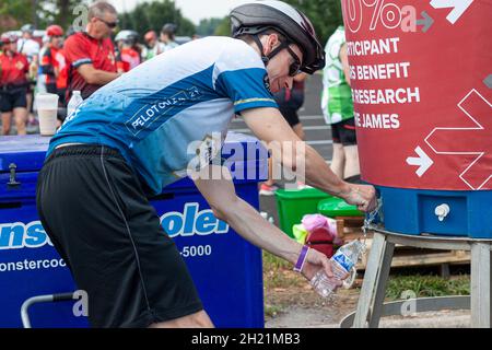 Columbus, OH USA 08-07-2021: Ein kaukasischer Mann mit Fahrradhelm füllt seine Plastikwasserflasche aus einem großen Wasserspeicher während eines sp Stockfoto