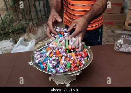 Nablus, Palästina. Oktober 2021. Ein Palästinenser verteilt Süßigkeiten anlässlich der Geburt des Propheten Muhammad. Palästinenser schmücken die Straßen der Altstadt von Nablus anlässlich des Geburtstages des Propheten. Muslime feiern den Geburtstag des Propheten jedes Jahr am zwölften von Rabi' al-Awwal, dem dritten Monat des islamischen Kalenders. Kredit: SOPA Images Limited/Alamy Live Nachrichten Stockfoto