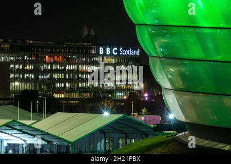 Glasgow, Schottland, Großbritannien. Oktober 2021. IM BILD: Nachtansicht des COP26-Geländes und des Veranstaltungsortes mit temporären Strukturen, die zur Hälfte auf dem Gelände des Scottish Event Campus (SEC) errichtet wurden, das früher als Scottish Exhibition and Conference Center (SECC) bekannt war, mit dem vorderen Parkplatz außerhalb des neu benannten OVO Hydro (ehemals SSE Hydro) Mit neuen Transfers über den Steg, die sagen, „die Menschen machen Glasgow“ und Nachtarbeiter machen weiterhin Vorbereitungen. Quelle: Colin Fisher/Alamy Live News Stockfoto