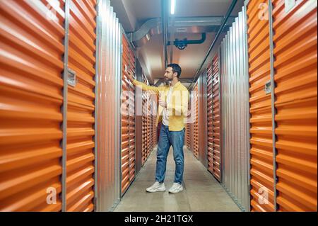 Mann mit Tablett berührt die Behältertür Stockfoto