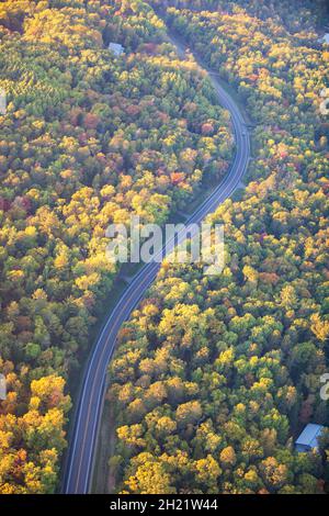 Luftaufnahme der kurvigen Straße zwischen Bäumen in Herbstfarben im Norden von Minnesota Stockfoto