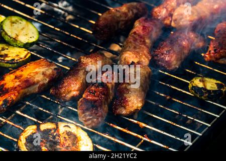 Szenische Aufnahme von gegrillten Fleischbrötchen namens Mici oder mititei mit Gemüse auf dem Barbeque Stockfoto