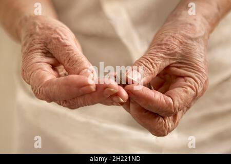 Die faltigen Hände der alten Frau zählen kleine Münzen Stockfoto
