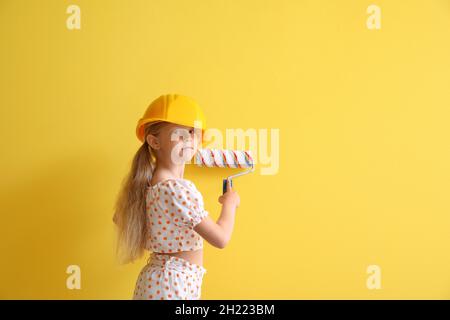 Kleines Mädchen in Hardhat Malerei auf gelbem Hintergrund Stockfoto