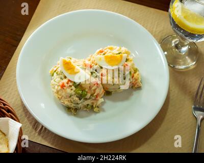 Russischer Salat aus gewürfeltem gekochtem Gemüse, garniert mit Eiervierteln Stockfoto