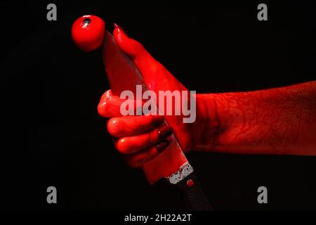 Hand mit blutbeflecktem Messer und Augenball auf schwarzem Hintergrund Stockfoto