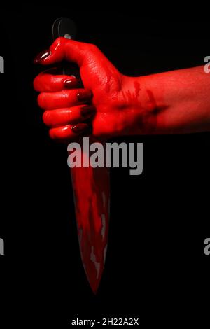 Hand mit blutbeflecktem Messer auf schwarzem Hintergrund Stockfoto