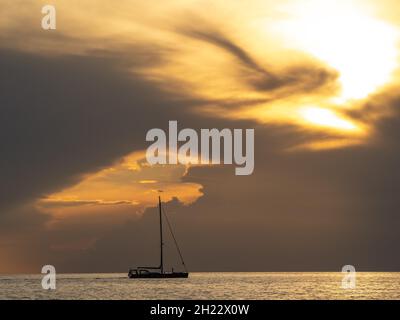 Segelschiff mit zusammengerafften Segeln vor dunklen Wolken, Sonnenuntergang, Adria, Istrien, Slowenien Stockfoto