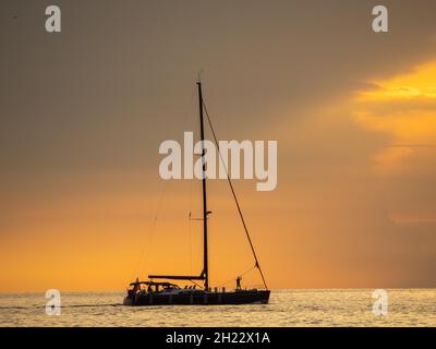 Segelschiff mit zusammengerafften Segeln vor dunklen Wolken, Sonnenuntergang, Adria, Istrien, Slowenien Stockfoto