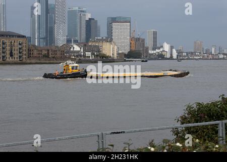 Schlepper SWS ESSEX schiebt eine Seekahn vorbei an Canary Wharf, Thames, London, Großbritannien Stockfoto