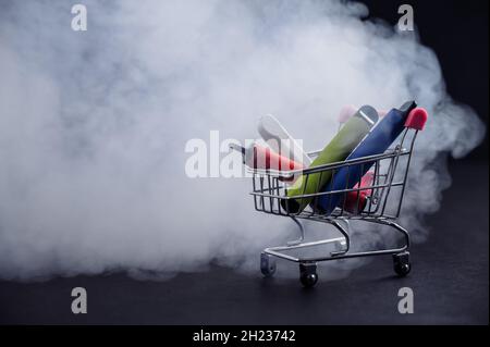 Einwegvapes in einem Warenkorb auf schwarzem Hintergrund. Moderne elektronische Zigaretten. Stockfoto